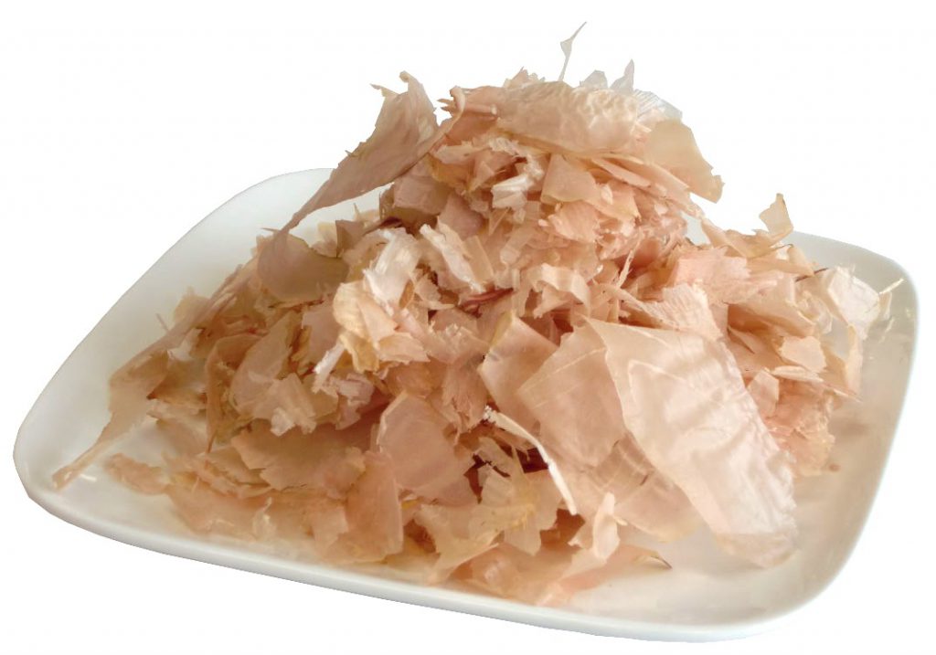 Bonito flakes are slices of dried and thinly shaved fish. They're not just paper thin, they're tissue paper thin. They're packed with meaty, slightly salty flavor and make a great topping for ramen (in moderation). You definitely don't want to overdo it because it can really overpower a dish.